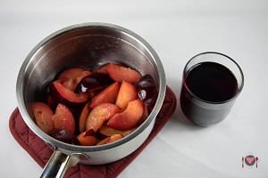 La foto raffigurante le prugne e il vino rosso per la preparazione delle prugne cotte