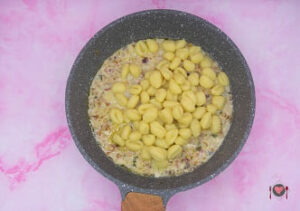 La foto raffigurante l'aggiunta degli gnocchi nel sugo, per la preparazione degli Gnocchi gorgonzola speck e noci