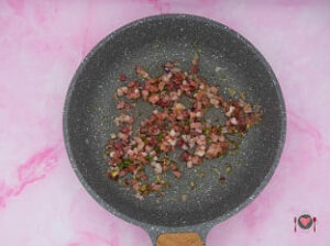 La foto raffigurante lo speck gettato in padella, per la preparazione degli Gnocchi con gorgonzola e speck