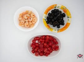 La foto raffigurante i gamberetti, le olive e i pomodorini per la preparazione della Pasta fredda con pesto e gamberetti