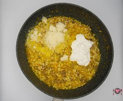 La foto raffigurante l'aggiunta di panna e formaggio per la preparazione del Risotto con la zucca e salsiccia