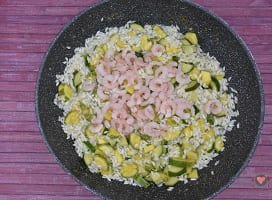 La foto raffigurantei gamberetti aggiunti al riso per la preparazione del Risotto zucchine e gamberetti