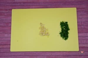 La foto raffigurante l'aglio e il prezzemolo tritati per la preparazione del pollo alle verdure