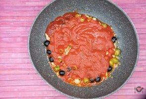 La foto raffigurante la salsa al pomodoro aggiunta in padella per la preparazione della pasta con tonno e olive