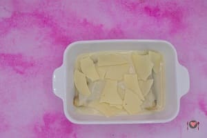 La foto raffigurante il formaggio a pezzi messo sulla besciamella per la preparazione dei finocchi gratinati al forno