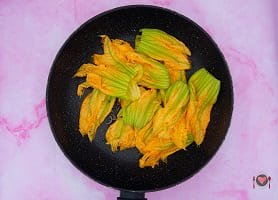 La foto raffigurante i fiori di zucca puliti e messi in padella assieme alla cipolla per la preparazione della frittata di fiori di zucca