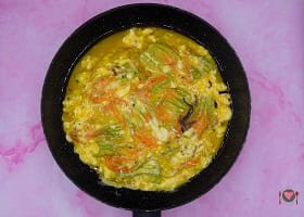 La foto raffigurante il composto a base di uova e fiori di zucca versati in padella per la preparazione della frittata di fiori di zucca