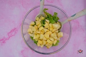 La foto raffigurante l'insalata e i pezzi di mela conditi per la preparazione delle insalate di mela