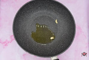 La foto raffigurante gli spicchio di aglio rosolati in padella assieme all'olio per la preparazione della frittata di spinaci