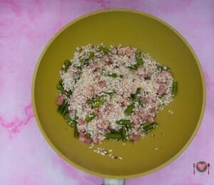 La foto raffigurante l'aggiunta del riso, per la tostatura del Risotto asparagi e pancetta